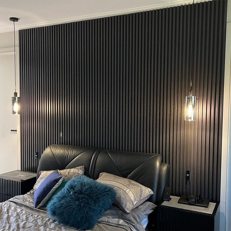 Bedroom with a black batten feature wall and pendant lights each side of the bed