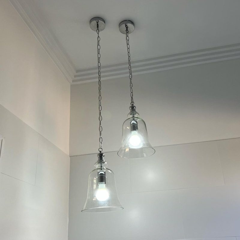Two clear glass bell pendant lights hanging from a high ceiling