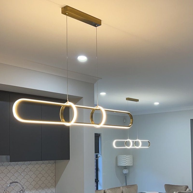 Gold ring-shaped LED pendant lights above a kitchen bench