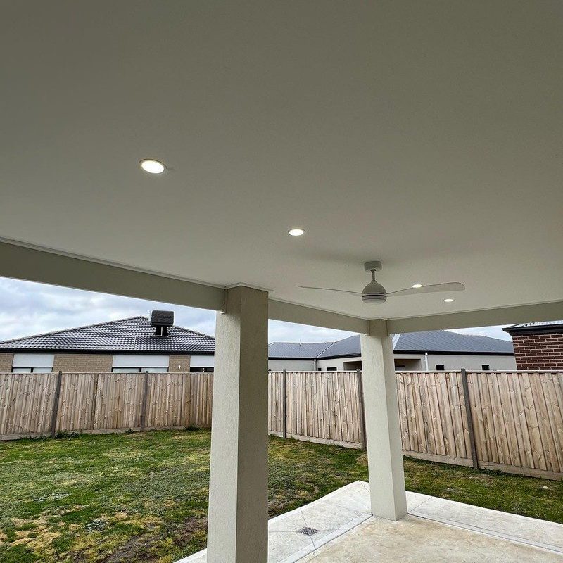 Covered alfresco with downlights and a ceiling fan facing a backyard