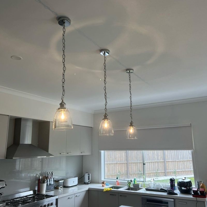 Three glass pendant lights hanging above a kitchen sink and window