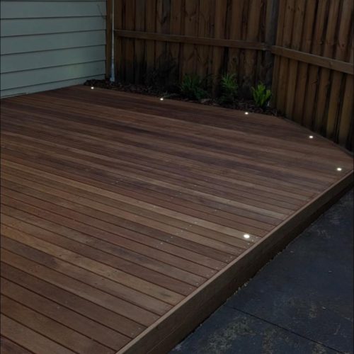 The same timber deck at dusk with its small deck lights switched on